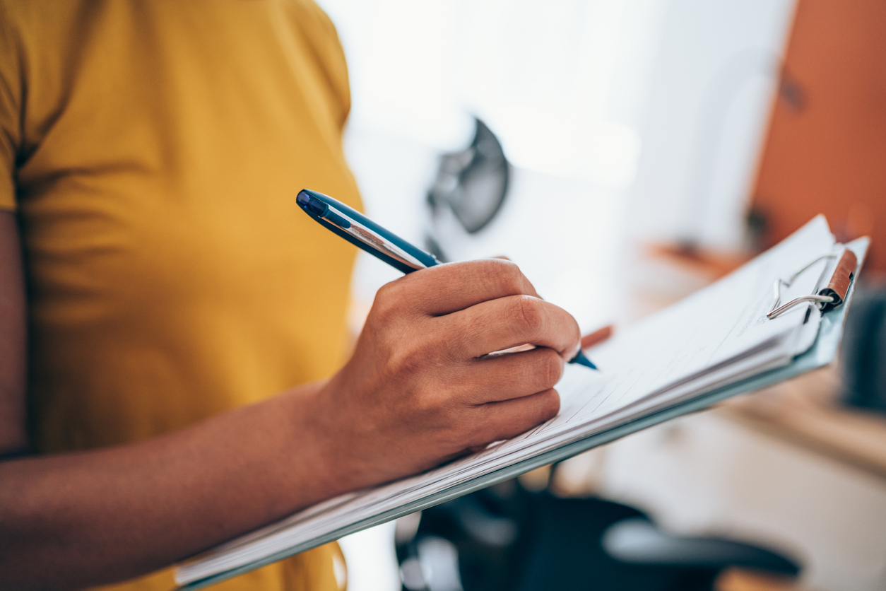 Woman hand writing on clipboard with a pen.